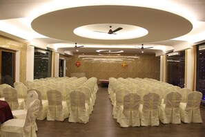 A conference room with rows of chairs, ceiling fans, and a decorative light fixture.