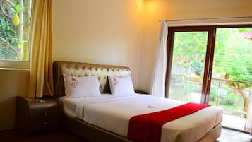 A hotel room with a bed, a nightstand, a window with curtains, and a view of greenery outside.