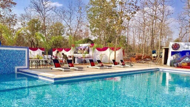 A swimming pool with lounge chairs and a covered area with tables.