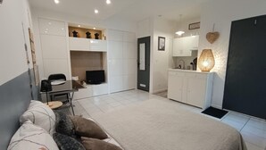 A compact living space with a sofa, a television, a kitchenette, and a dining area. - Studio LE COLONEL, in the heart💖of the beautiful village of Marseillan  (Marseillan)