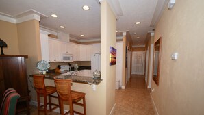 A kitchen with white cabinets, a granite countertop, and two wooden bar stools. - Gulf Breeze Condo #207- Private Boat Ramp! WiFi! Docks to be completed May 2026! (Steinhatchee)