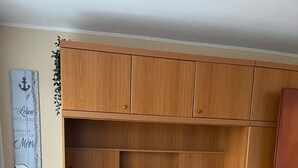 Un dormitorio con cama, cabecero de madera, mesita de noche con lámpara y decoración en la pared.