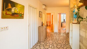 A hallway with a tiled floor, a painting on the wall, and a statue. - Apartments Sany - Two Bedroom Apartment with Balcony and Sea View (Cavtat)