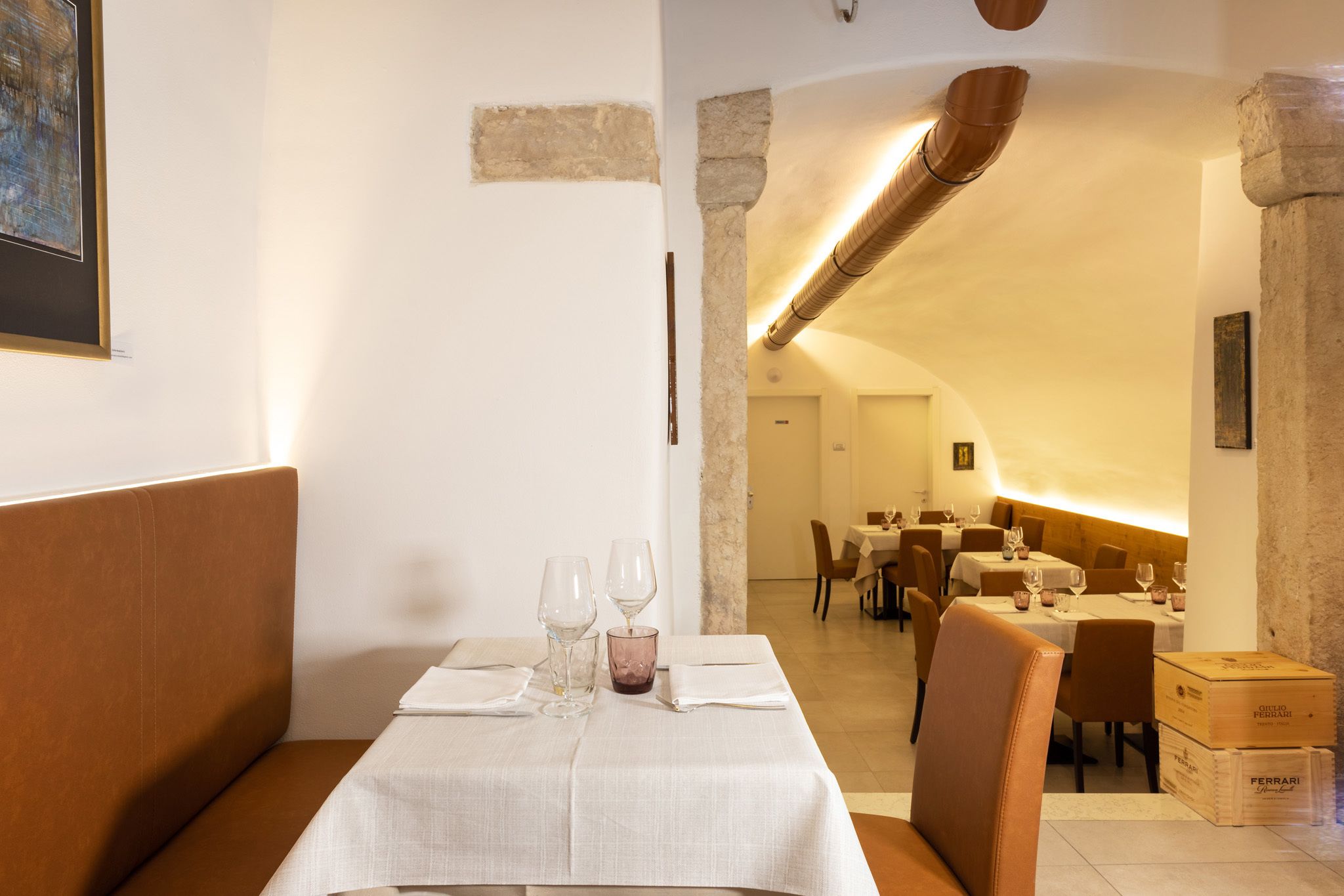 Een restaurant met een gedekte tafel voor twee, een bankje en uitzicht op de eetruimte.