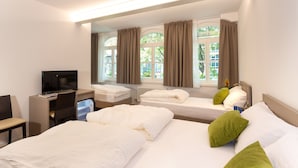 Habitación de hotel con dos camas, un escritorio con computadora y ventanas grandes con cortinas.