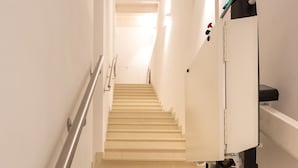 Una escalera con barandilla que lleva a un rellano con una lámpara y un panel de control.