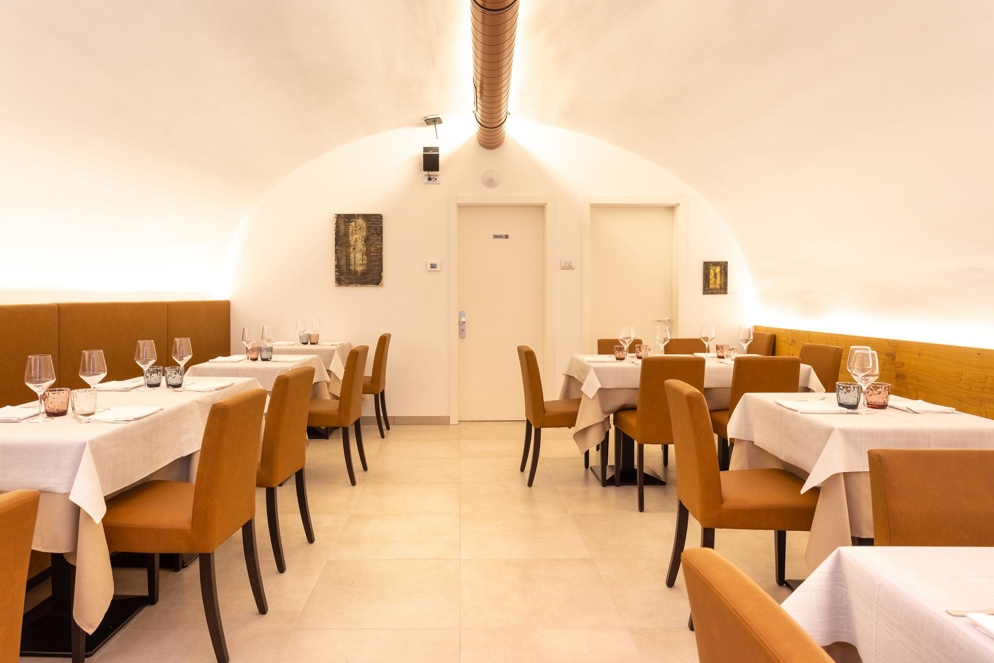 A restaurant with tables set for dining, chairs, and a white ceiling.
