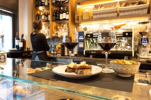 A bar area with a glass display case, a plate with food, two wine glasses, and a bowl of snacks.