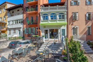 A building with a green awning, outdoor seating, and a staircase leading to the entrance.