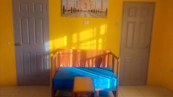 Une pièce avec un lit, une petite table et deux portes.