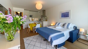 A modern hotel room with a bed, bedside table, and a dining area with a table and chairs. - Large studio, feet in the water! (Bénodet)