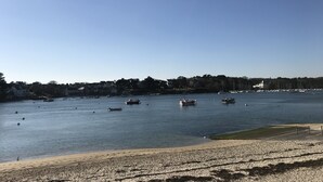 A coastal view with boats on the water, a sandy beach, and buildings in the background. - Large studio, feet in the water! (Bénodet)