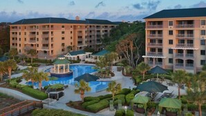 Ein Hotel mit mehreren Stockwerken, einem Schwimmbad und Außenbereichen mit Sitzgelegenheiten.