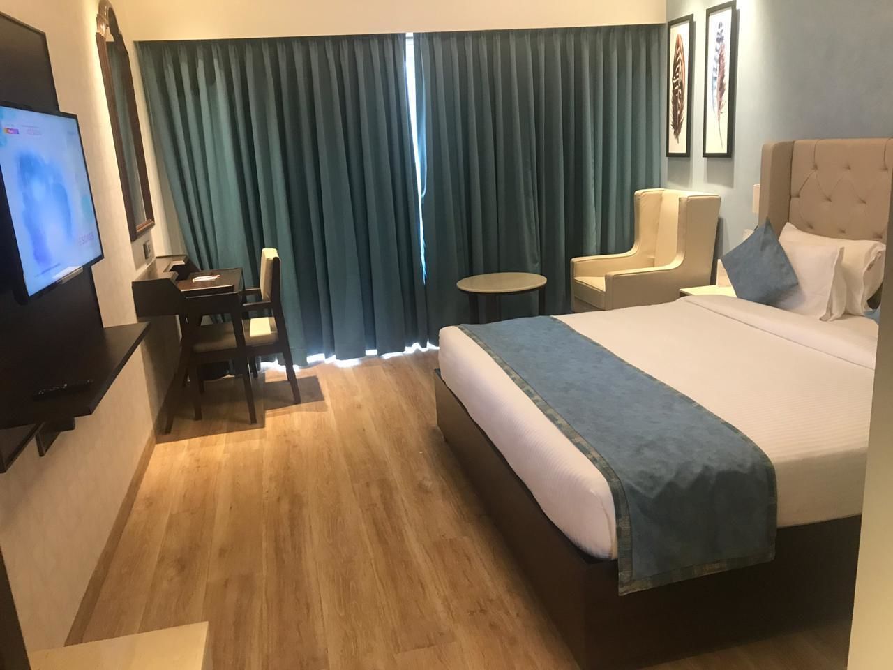 Habitació d'hotel amb llit, escriptori, cadira, taula petita i televisió.