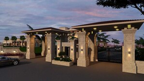 A hotel entrance with a covered driveway, palm trees, and a gated entrance. - Enrise by Sayaji Rau (Indore)