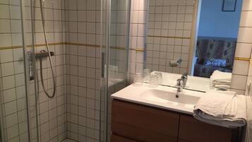 Une salle de bain avec une douche, un lavabo et un miroir.