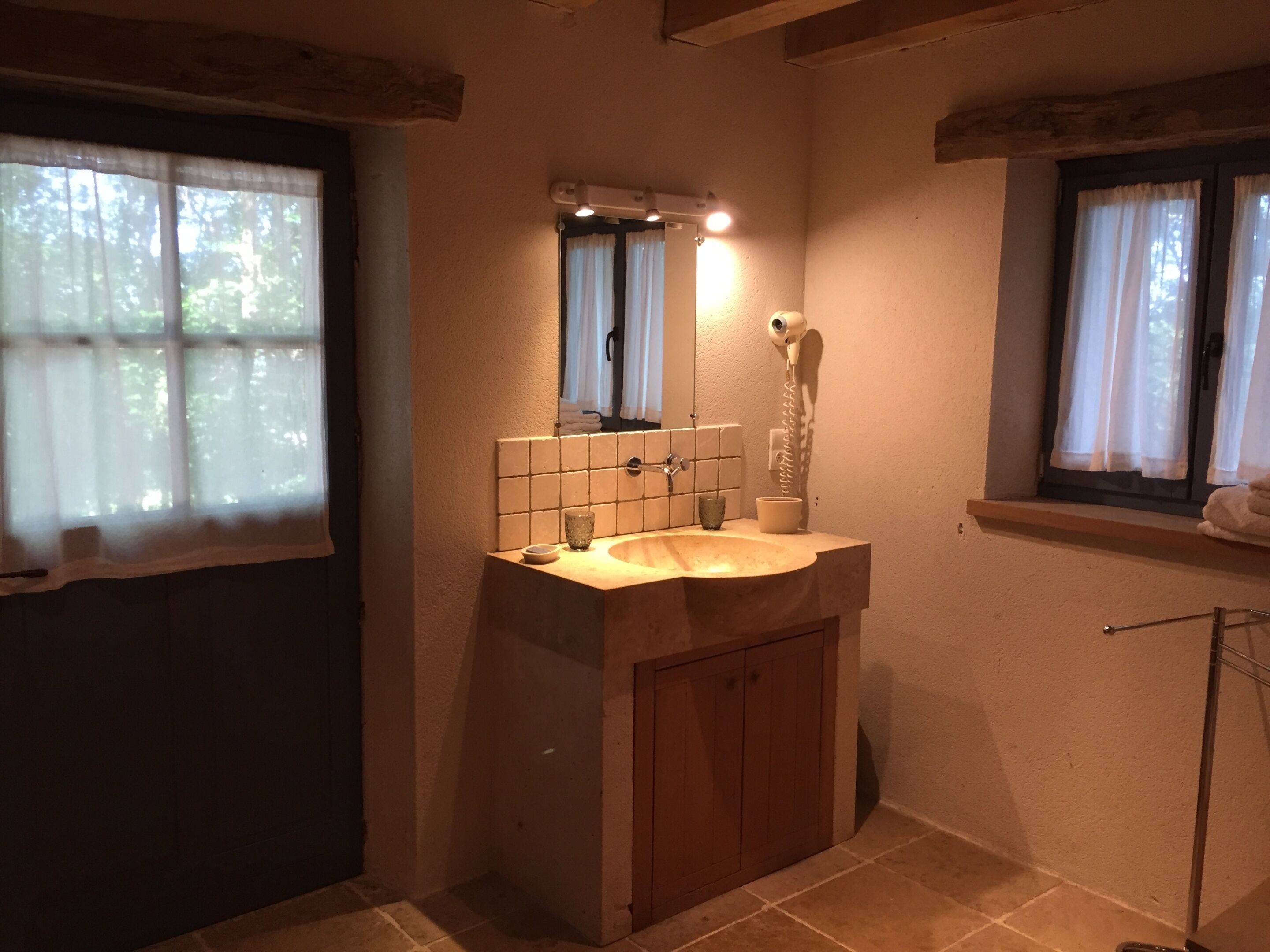 Ein Badezimmer mit Waschbecken, Spiegel und einem an der Wand befestigten Föhn.