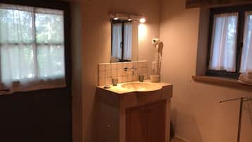 Ein Badezimmer mit Waschbecken, Spiegel und einem an der Wand befestigten Föhn.