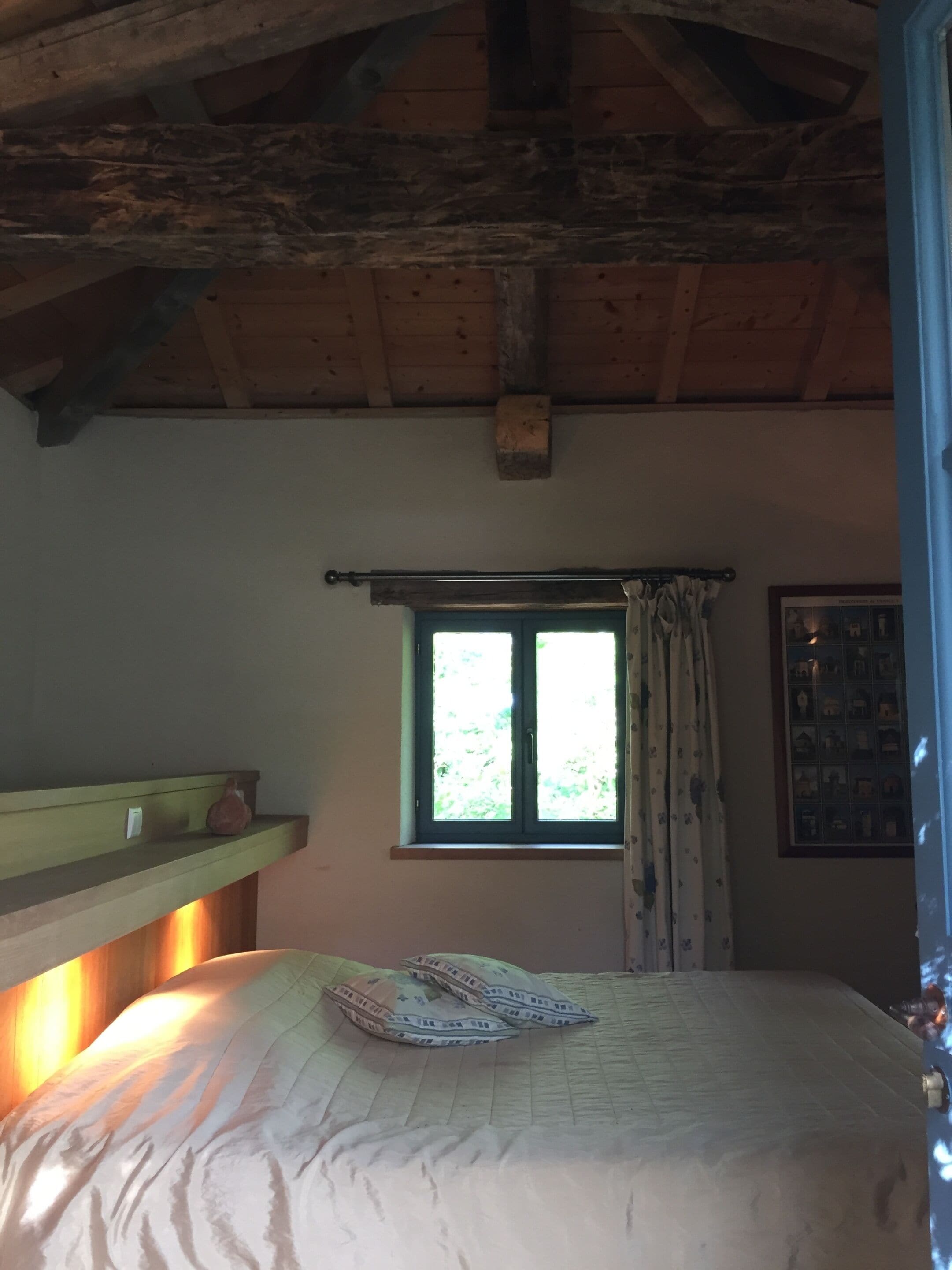 Ein Schlafzimmer mit Bett, einem fensterbepflanzten Fenster, einem Regal mit Vogel und einem gerahmten Bild an der Wand.