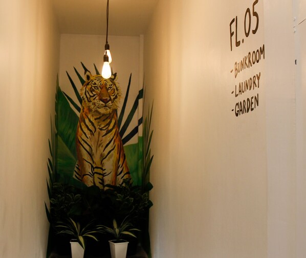 A hallway with a wall-mounted sign listing rooms: Bunkroom, Laundry, Garden. - Tropical Summer Hostel (Bangkok)