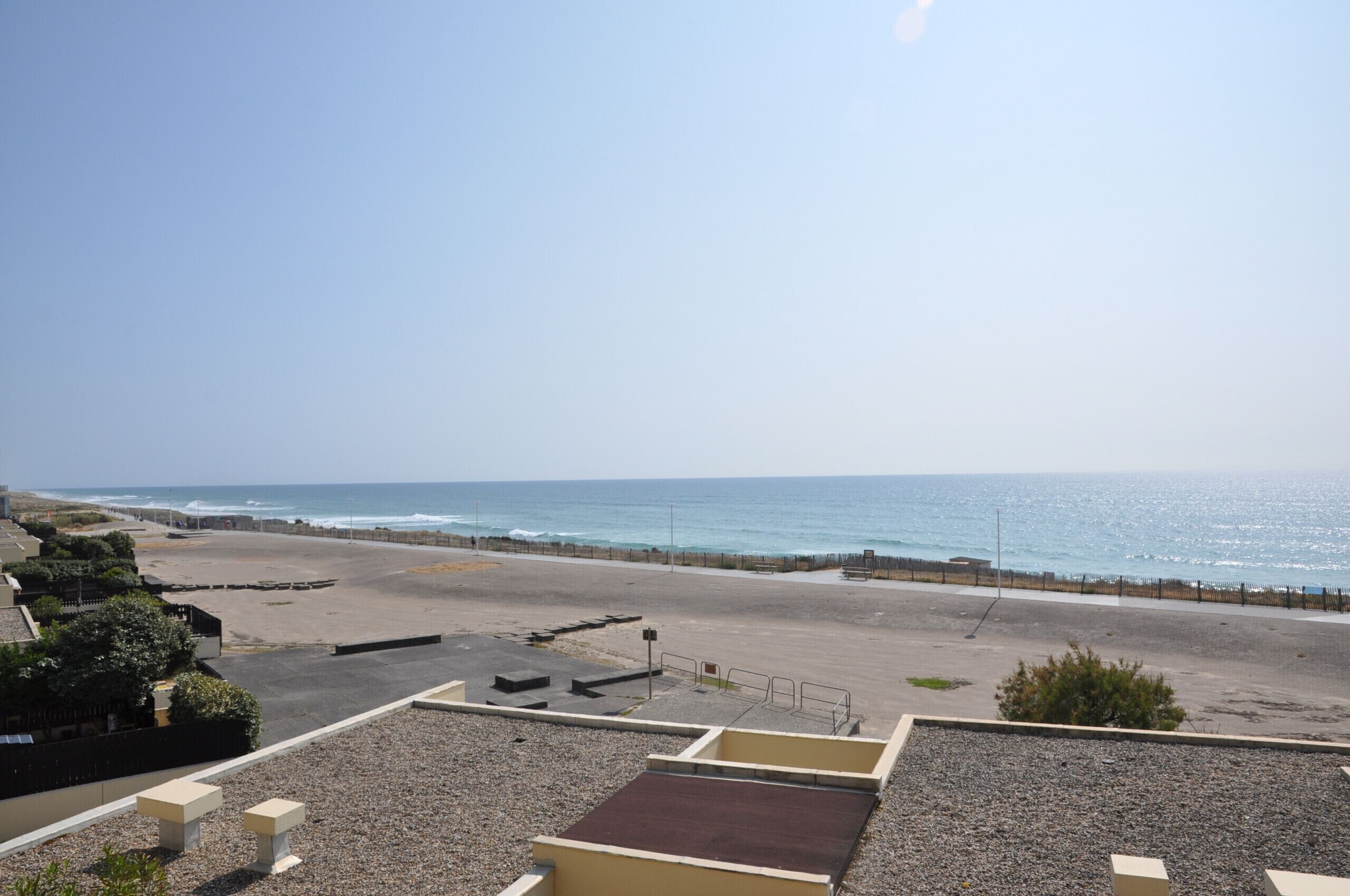 Vista a la playa desde una terraza en la azotea, bajo un cielo despejado.