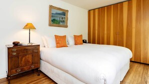 A bedroom with a large bed, wooden wardrobe, a nightstand with a lamp, and a framed picture on the wall. - Ladbroke Walk, by Veeve (London)