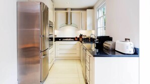 A modern kitchen with stainless steel appliances, white cabinetry, and a black countertop. - Ladbroke Walk, by Veeve (London)