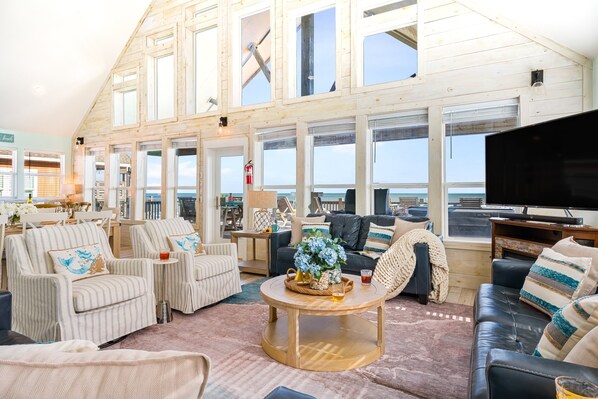 A spacious living area with a large TV, comfortable seating, and a view of the ocean.