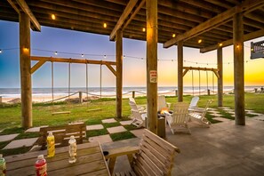 A wooden deck with seating, a fire pit, and a view of the ocean.