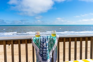 A wooden deck with a tablecloth and two glasses of water. - Beachfront | Game Room, Hot Tub & Ocean Views (Bolivar Peninsula)