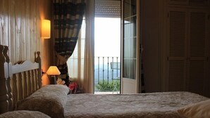 Een slaapkamer met twee bedden, een nachtkastje, een lamp en uitzicht op de omgeving door een schuifdeur.