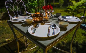 A table set outdoors with plates, cutlery, and a lantern.