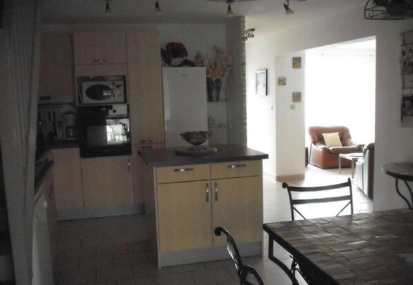 A compact kitchen with a refrigerator, microwave, and a small dining area with a table and chairs.