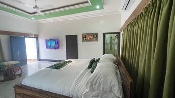 Une chambre d’hôtel avec un lit, une télévision, un panneau indiquant la sortie, une porte et une fenêtre.