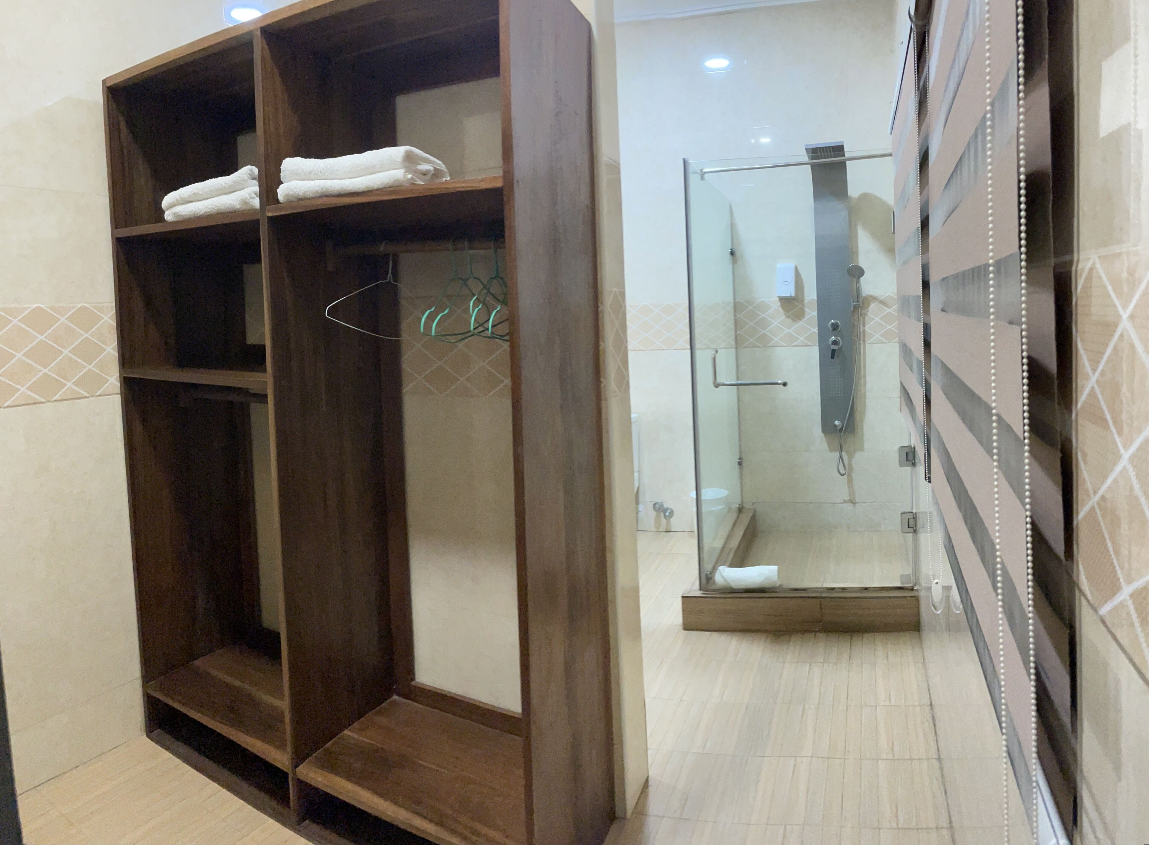 A bathroom with a wooden vanity, a glass shower enclosure, and tiled walls.