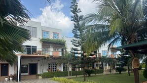 Un patio con suelo de baldosas decorativas, palmeras y un edificio con varias ventanas y balcones.