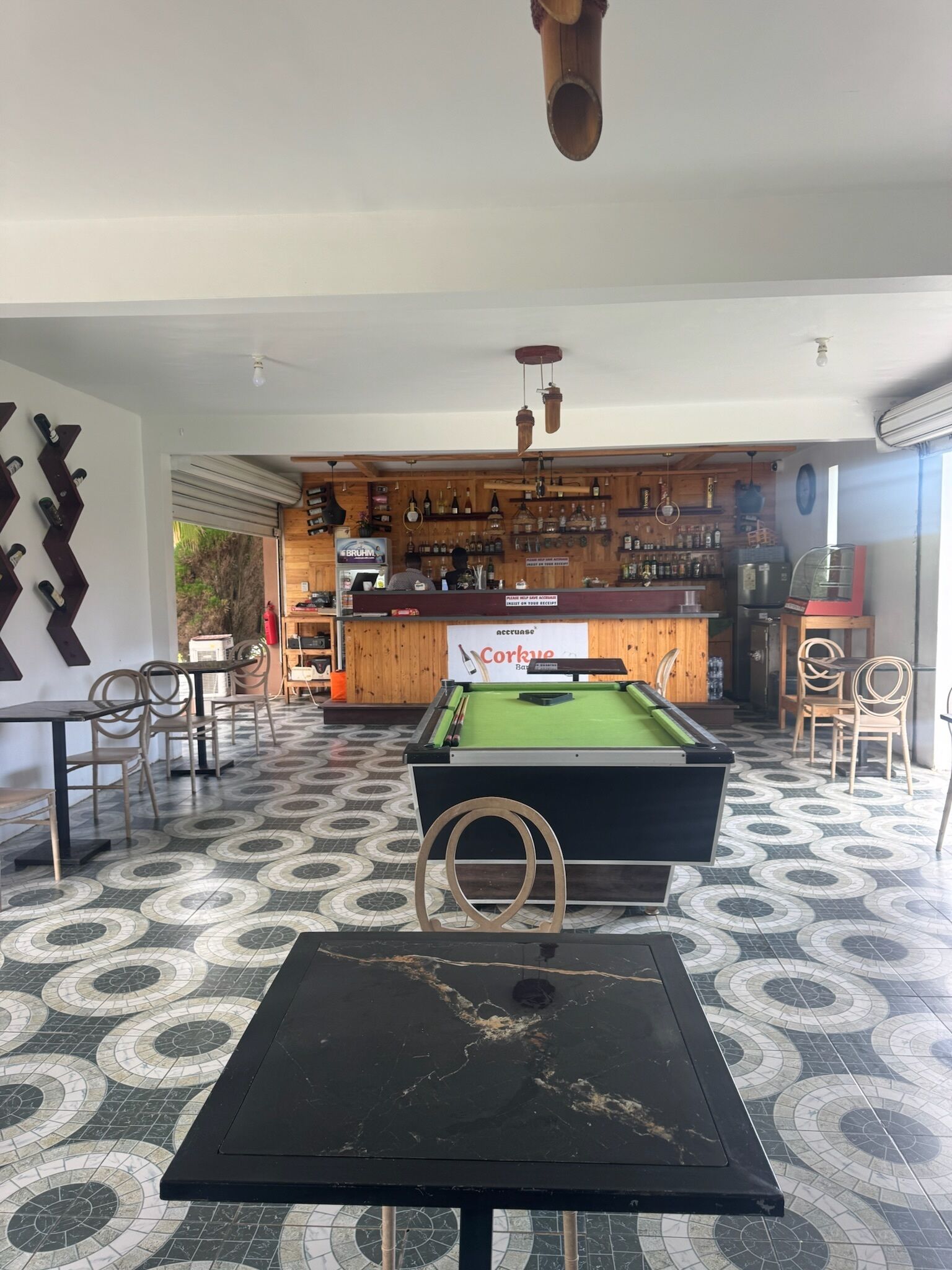 A billiards table, chairs, a pool table, a bar area with bottles, and a sign for 'Corkue Bar'.