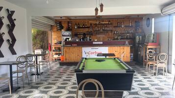 A billiards table, chairs, a pool table, a bar area with bottles, and a sign for 'Corkue Bar'.
