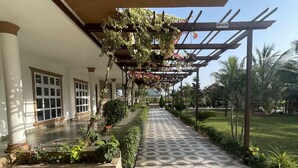 Un paseo techado con suelo estampado, una pérgola con plantas trepadoras y vistas del paisaje circundante.