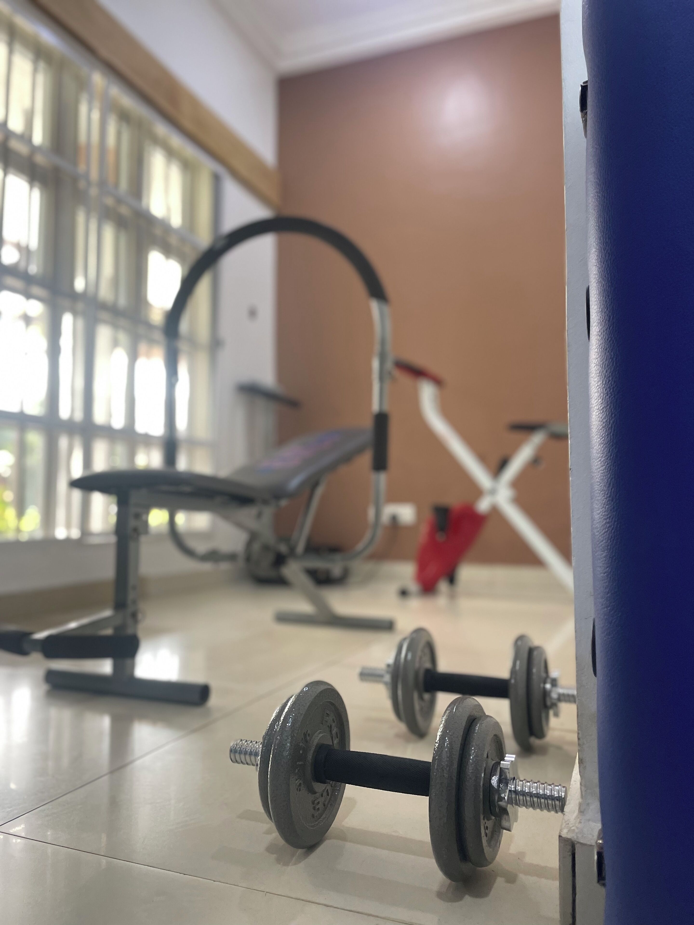 Un gimnasio con equipo de ejercicio, incluyendo mancuernas y una banca.