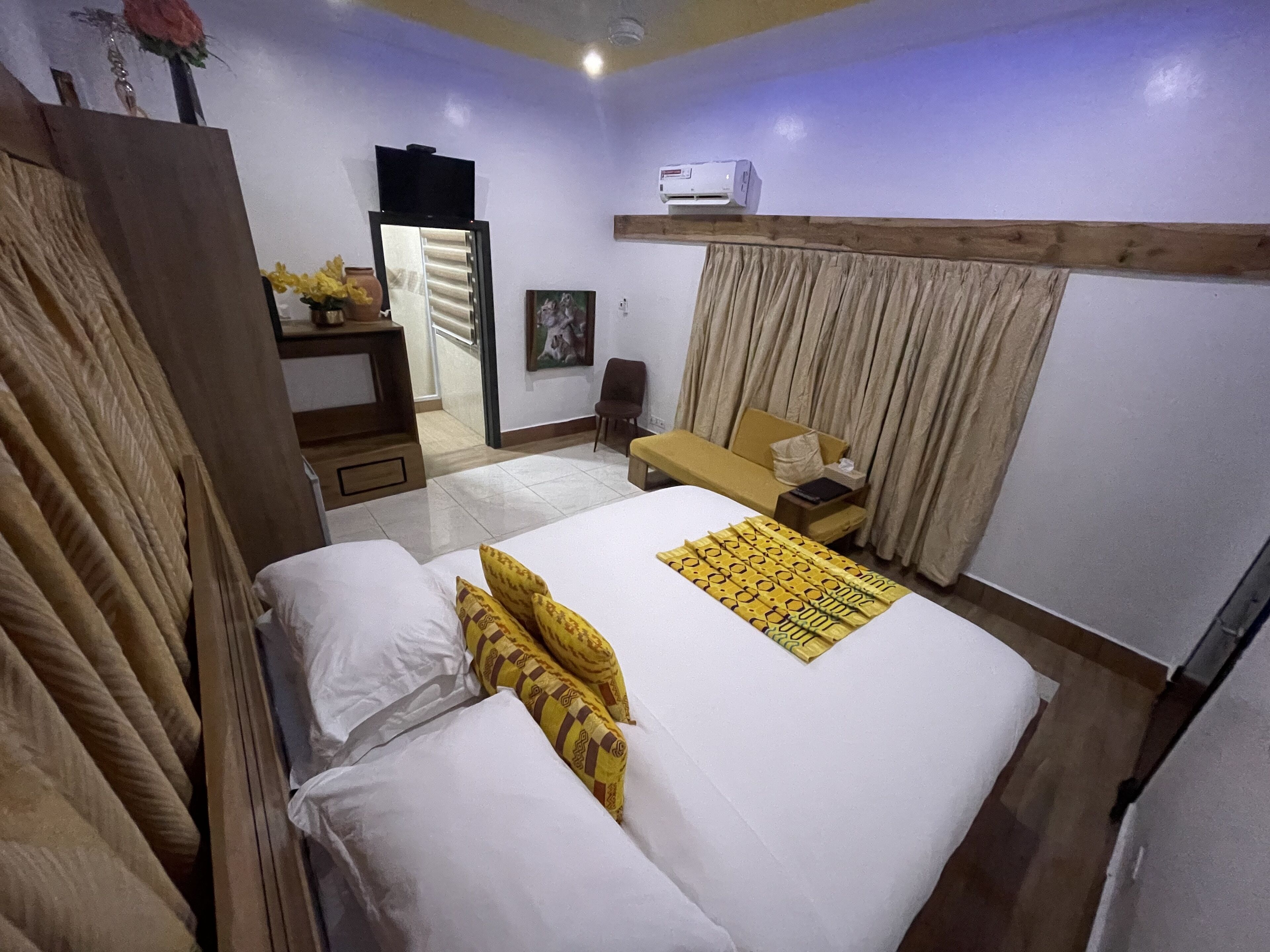 Une chambre d’hôtel équipée d’un grand lit, d’un bureau, d’une chaise, d’un climatiseur et d’un téléviseur.