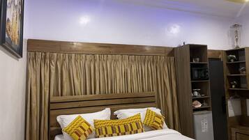 A neatly made bed with patterned pillows, a wooden headboard, and a built-in shelving unit with various items.