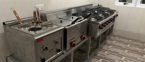 A commercial kitchen with stainless steel appliances, a tiled floor, and a window with a view of the outside.