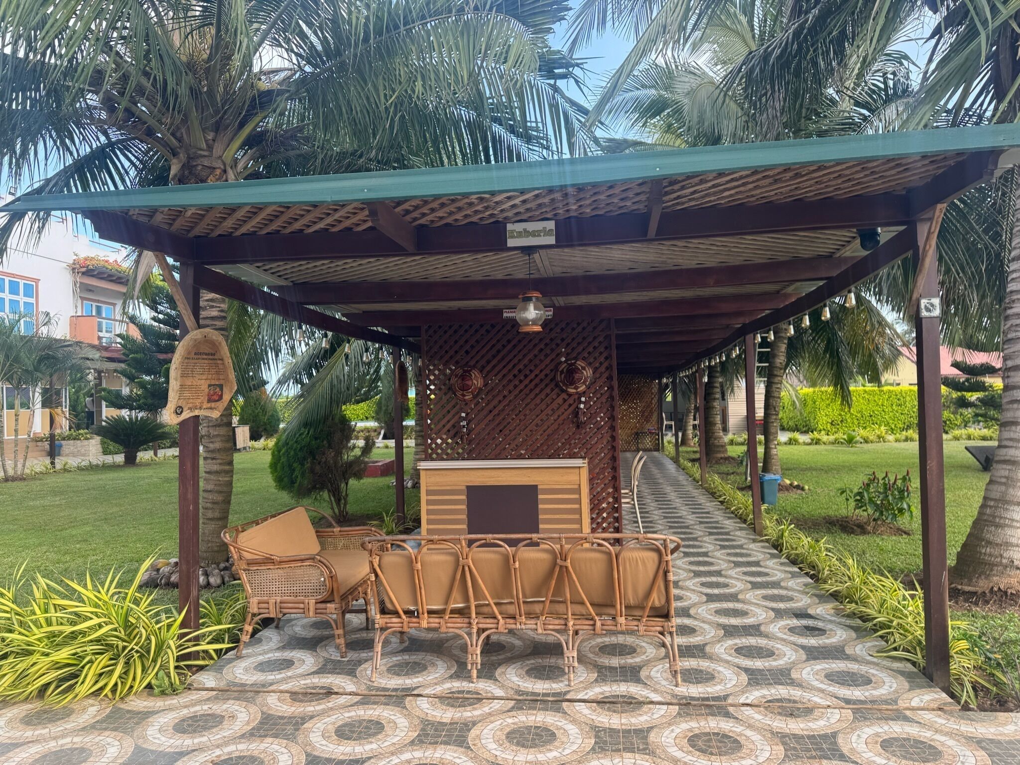 A covered outdoor seating area with wicker furniture and a patterned floor.