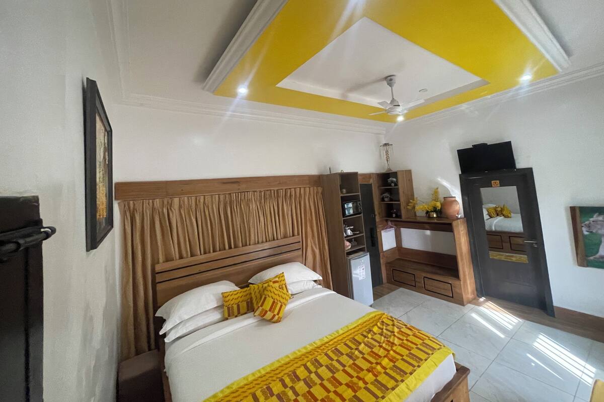 Quarto de hotel com cama, guarda-roupa, espelho e ventoinha no teto.