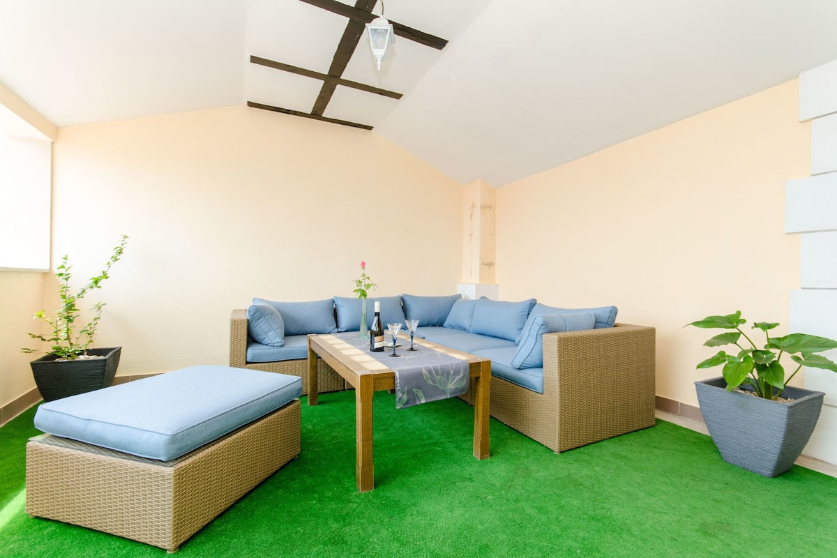 A cozy room with a blue sofa, a wooden table, and green artificial grass flooring.
