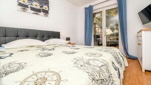 A bedroom with a bed, a headboard, a nightstand, a TV, and a window with curtains. - Apartments and Room Napoli (Bol)
