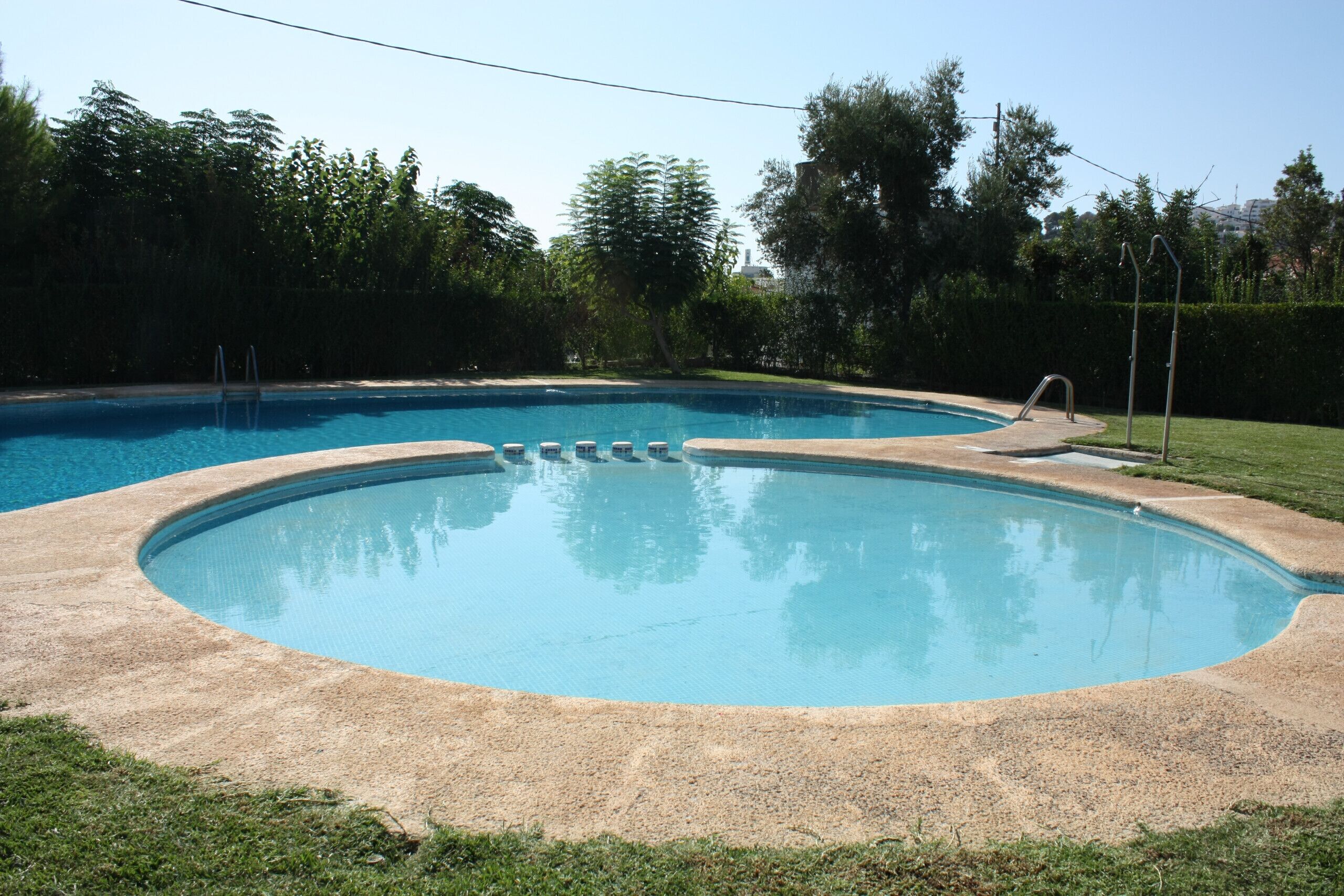 Una piscina con borde curvo y una pequeña zona de terraza.