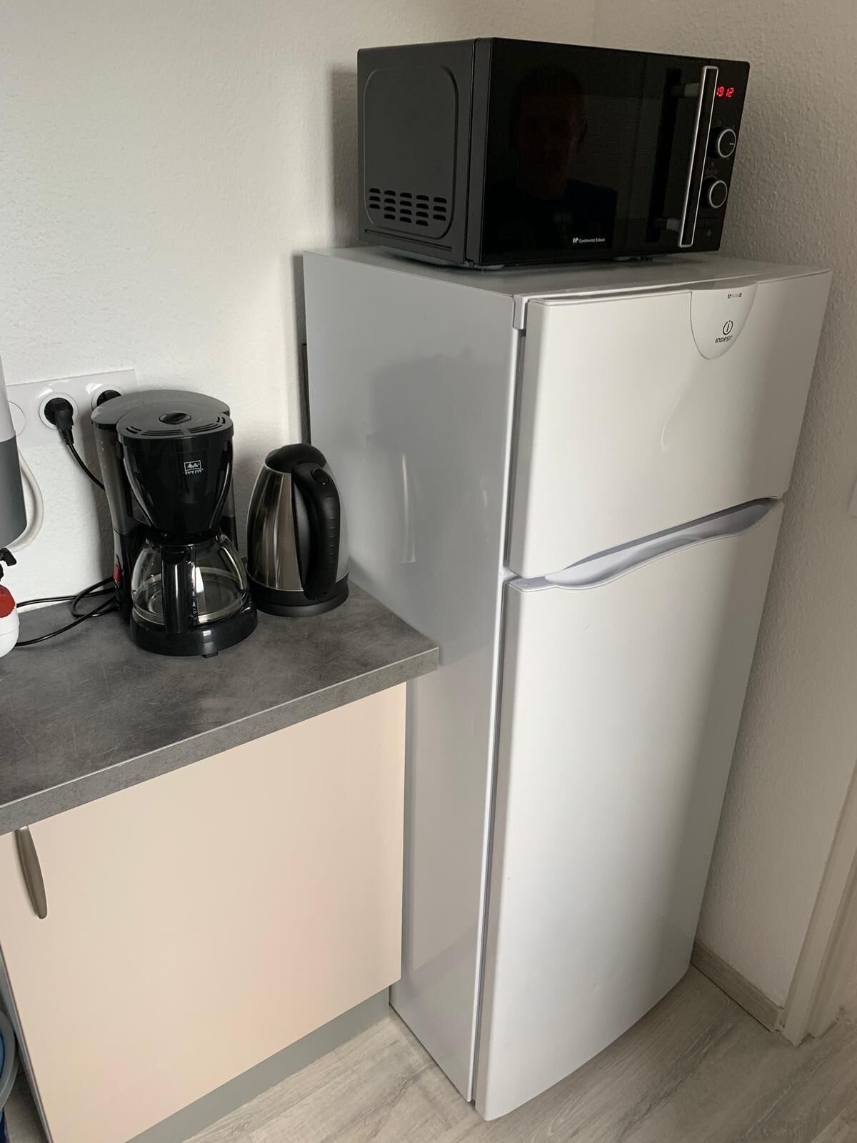Pieni, käytännöllinen keittiö, jossa on mikroaaltouuni, kahvinkeitin ja vedenkeitin työtasolla.