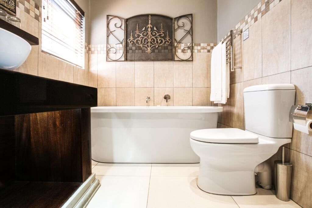 A modern bathroom with a bathtub, toilet, and a decorative wall piece above the bathtub.